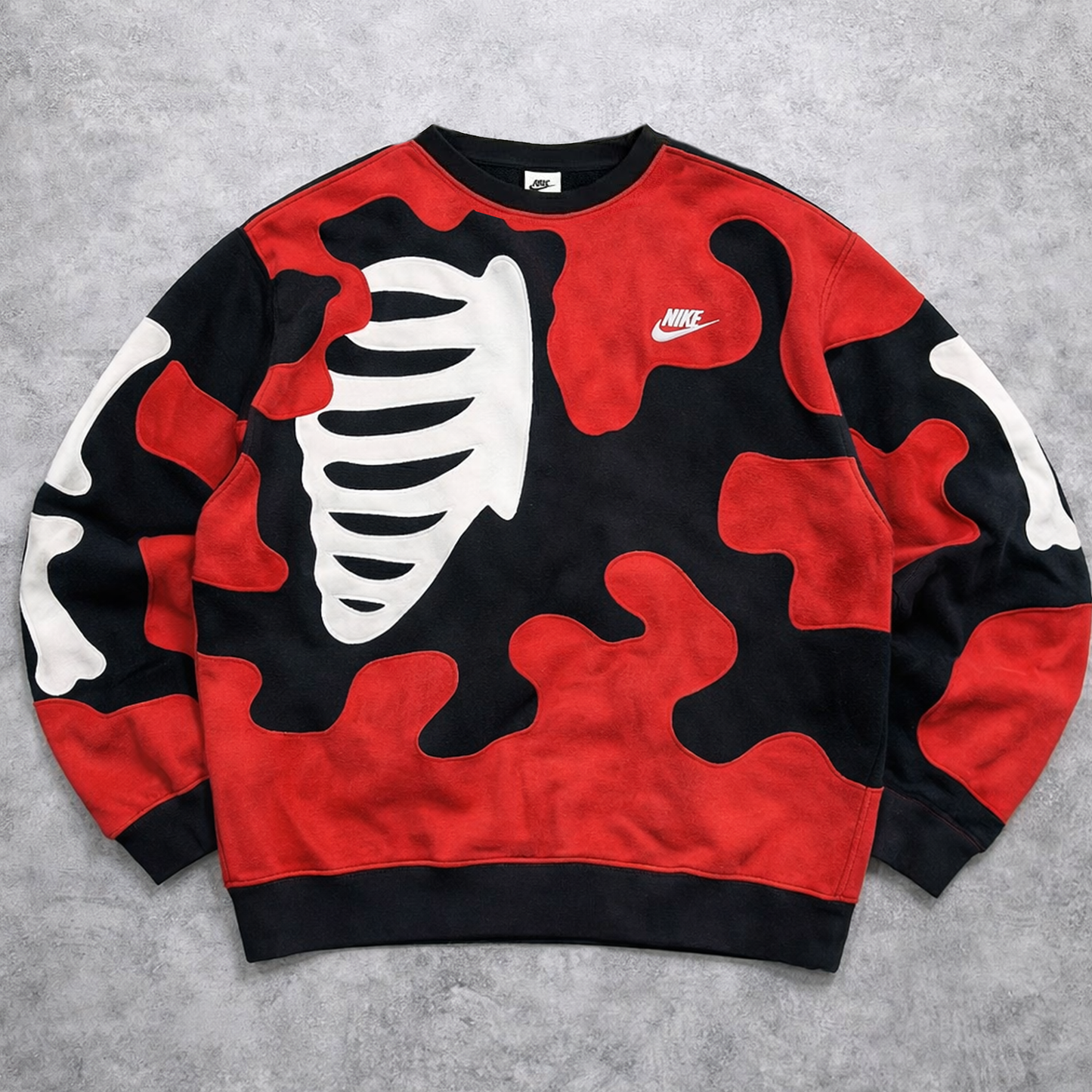 Red, black, and white camouflage-patterned sweatshirt with a Nike logo on a gray background